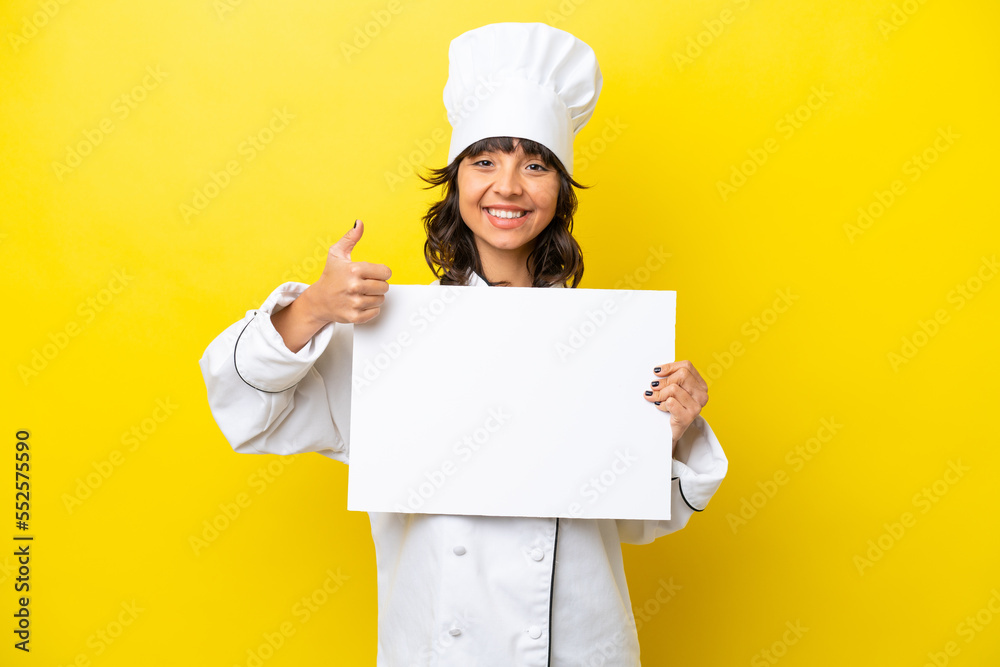 Young chef latin woman isolated on yellow background holding an empty placard with thumb up Young chef latin woman isolated on yellow background holding an empty placard with thumb up