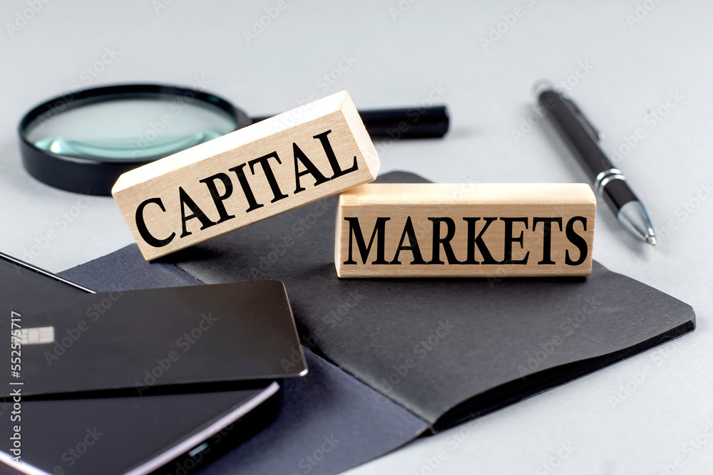 Fototapeta premium CAPITAL MARKETS text on wooden block on black notebook , business concept