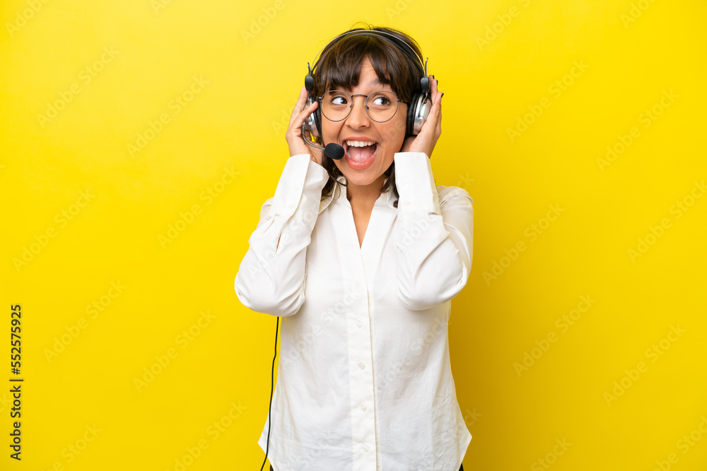 Telemarketer latin woman working with a headset isolated on yellow background Telemarketer latin woman working with a headset isolated on yellow background