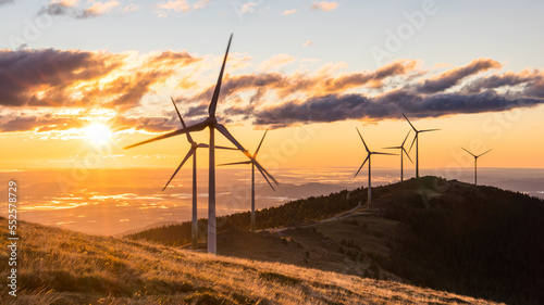 A group of wind mills on a mountain ridge during a beautiful sunrise
