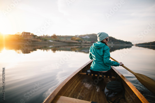 Woman paddling canoe on autumn lake