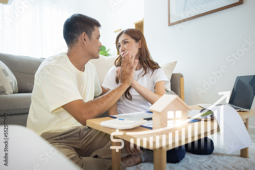 Asian couple in home or house. Include increasing graph, laptop, calculator and document on table. Concept for marriage, family, house value, market price, loan, finance, real estate and property. 