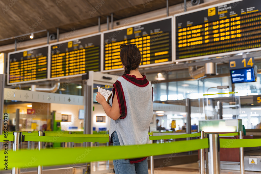 brunette girl with braid at the airport looking at the flight board