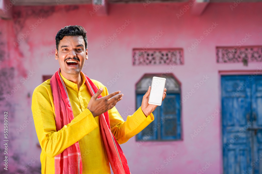 Happy Indian farmer showing smartphone screen at home Happy Indian farmer showing smartphone screen at home