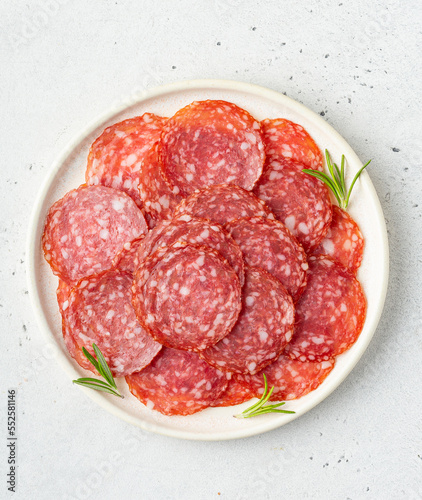 Thinly sliced salami sausage on a plate, top view