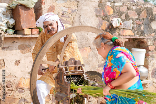 Old indian farmers couple using grass cutting machine at home. photo