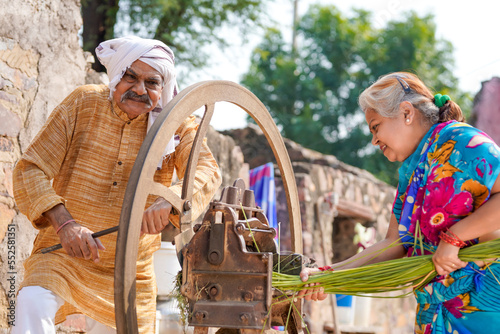 Old indian farmers couple using grass cutting machine at home. photo