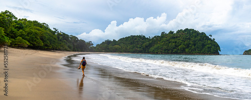 panorama of a tropical beach with palm trees in manuel antonio national park in quepos, Costa Rica; lone backpacker girl walking on a tropical paradise beach in Costa Rica