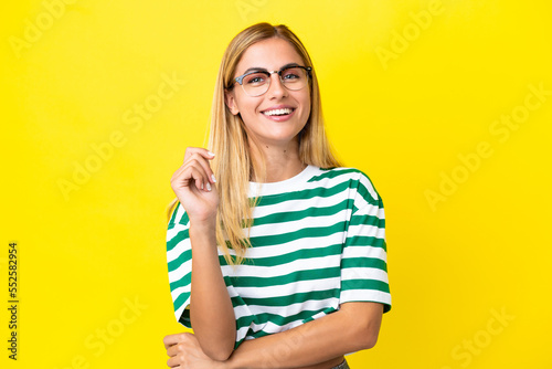 Blonde Uruguayan girl isolated on yellow background laughing