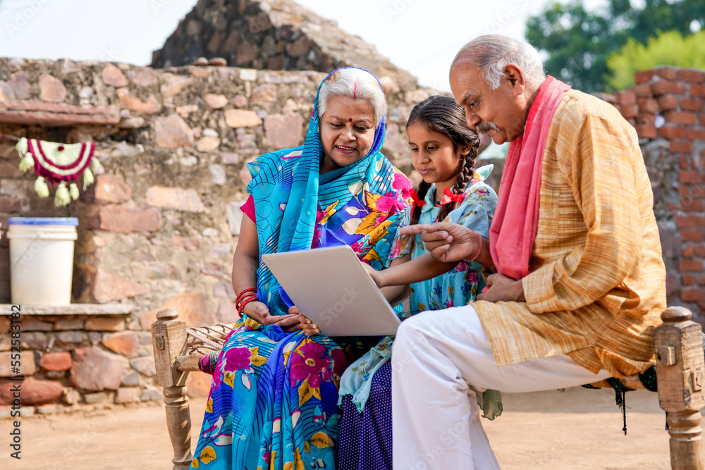 Indian little girl using laptop with grandparents.