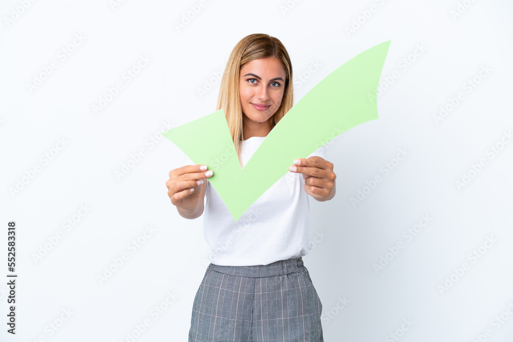 Blonde Uruguayan girl isolated on white background holding a check icon with happy expression Blonde Uruguayan girl isolated on white background holding a check icon with happy expression