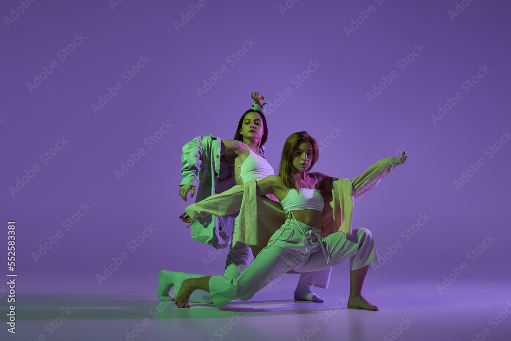 Obraz premium Dance performance. Stylish female dancers at contemporary choreography dance class isolated over crystal purple background. Style, youth, music and fashion