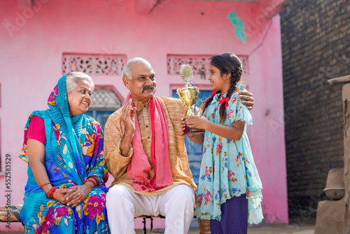 Indian little girl holding winning trophy with grandparents