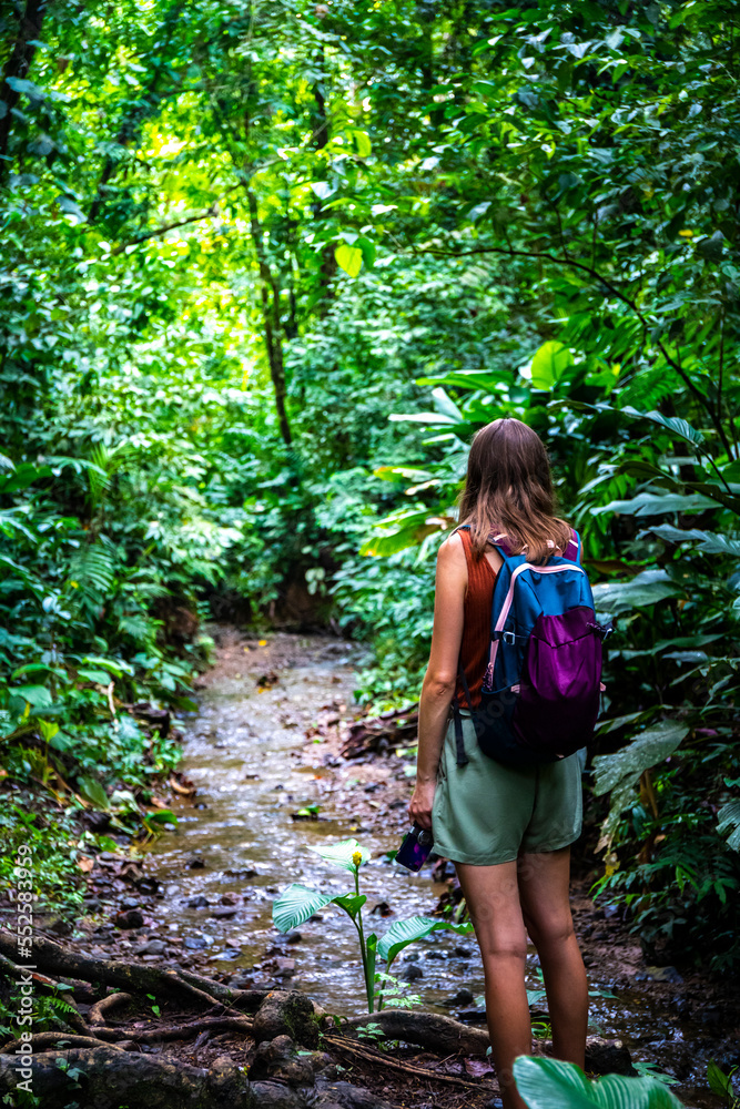 Backpacker girl walks through dense rainforest in Golfito National Wildlife Refuge; walking through wild tropical forest in Costa Rica Backpacker girl walks through dense rainforest in Golfito National Wildlife Refuge; walking through wild tropical forest in Costa Rica