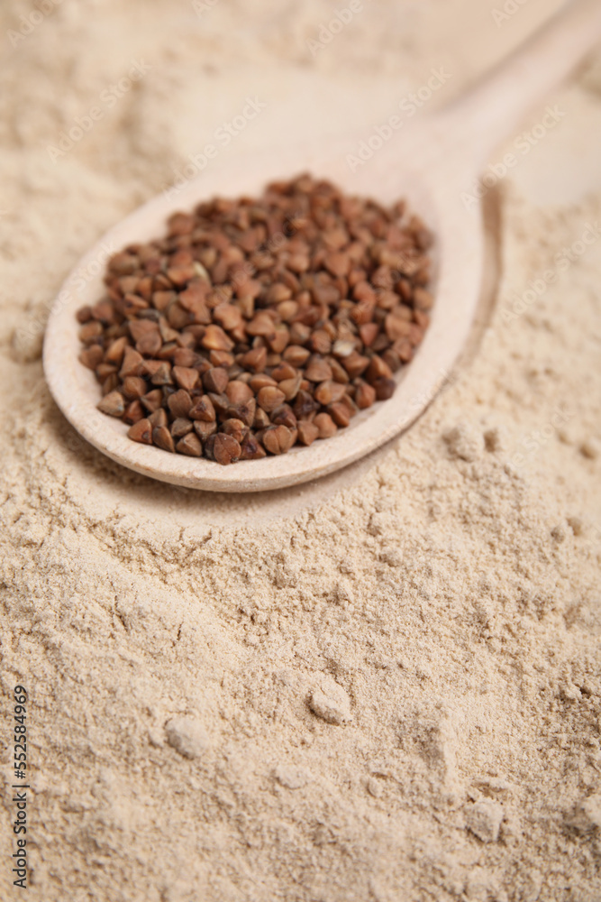 Spoon with buckwheat grains on flour, closeup Spoon with buckwheat grains on flour, closeup