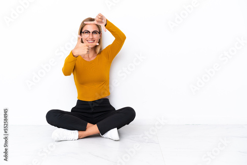 Blonde Uruguayan girl sitting on the floor focusing face. Framing symbol