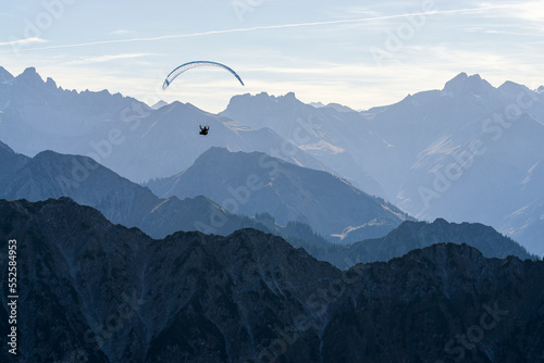 Paraglider flying above blue Mountains Silhouette, Allgaeu, Oberstdorf, Alps, Germany. Travel destination. Freedom and Holiday concept.