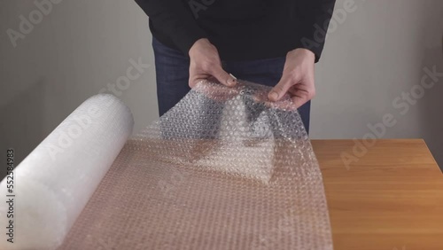Close-up of a man's hands unfolding an air bubble wrap at a table