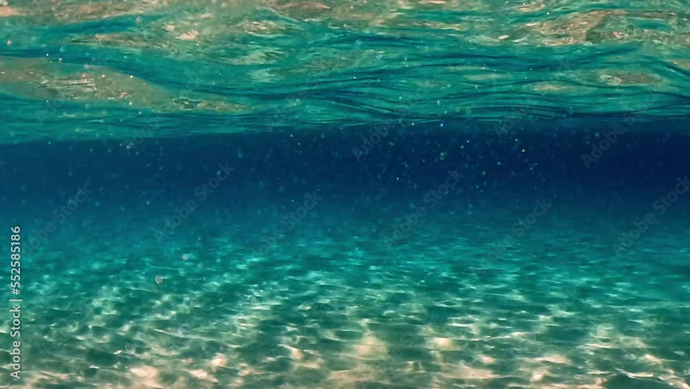 Authentic under water scene of crystalline turquoise tropical ocean water with rippled surface and reflections on seafloor with blue background and particles floating. Slow motion Authentic under water scene of crystalline turquoise tropical ocean water with rippled surface and reflections on seafloor with blue background and particles floating. Slow motion