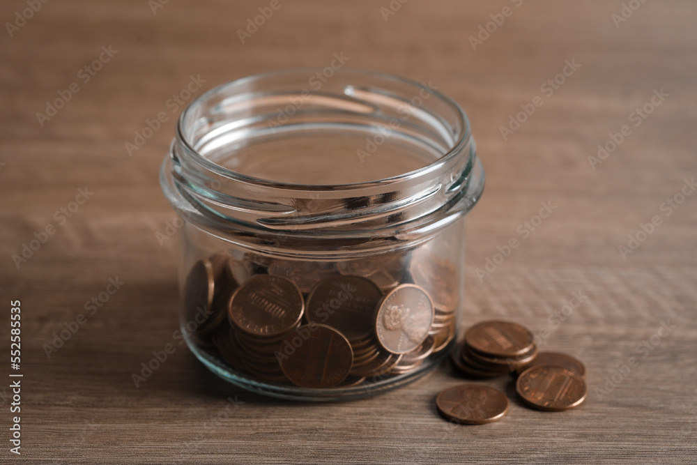 Glass jar with coins on wooden table Glass jar with coins on wooden table