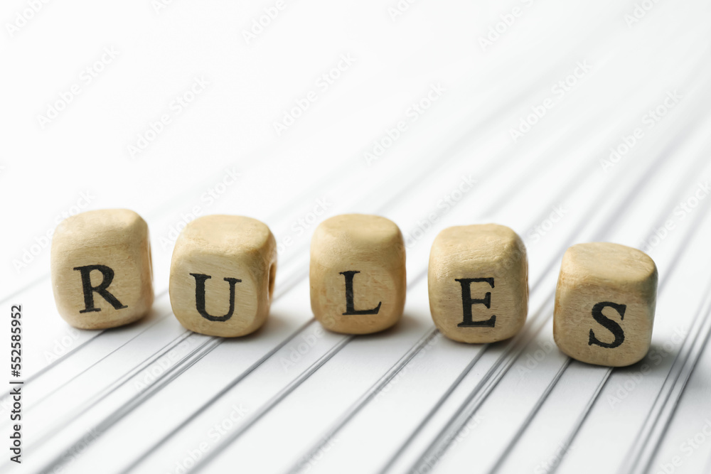 Word Rules made of wooden cubes with letters and books on white paper Word Rules made of wooden cubes with letters and books on white paper
