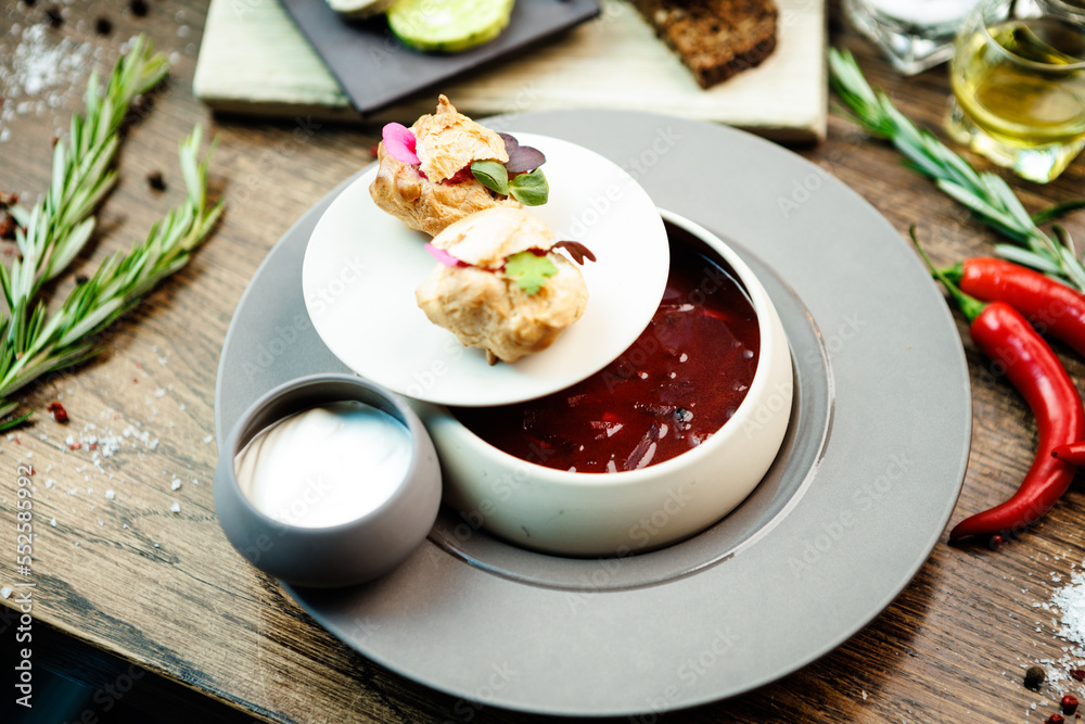 Beetroot soup Borscht with meat and sourcream in a bowl. Delicious healthy Ukrainian traditional food closeup served for lunch on a table in modern gourmet cuisine restaurant Beetroot soup Borscht with meat and sourcream in a bowl. Delicious healthy Ukrainian traditional food closeup served for lunch on a table in modern gourmet cuisine restaurant