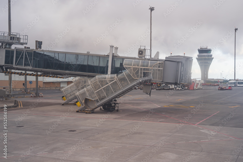 Access gangway to the aircraft and its control tower on a gray and dark day.