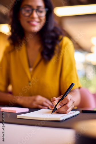 Mature Businesswoman Working At Desk In Office Writing In Notebook