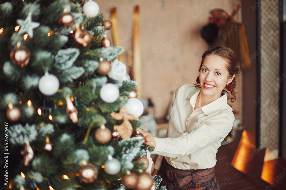 beautiful young woman decorating Christmas tree in her living ro