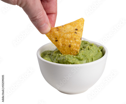 A hand dipping nachos in guacamole sauce