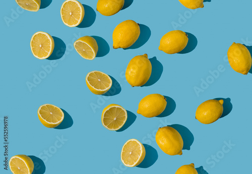 Diagonal summer pattern made with fresh yellow and lemon slices on bright blue pastel background. Minimal background summer concept on bright sunlight with sharp shadows
