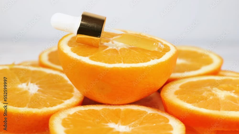 Vitamin c skin care serum.Anti-wrinkle fluid serum with antioxidant action.dropper pipette rotating on orange slices and white background.skin and face care concept.
