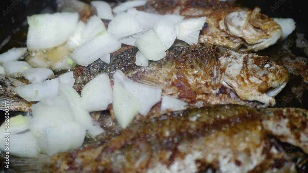 adding chopped onion to the pan where the fish is fried adding chopped onion to the pan where the fish is fried