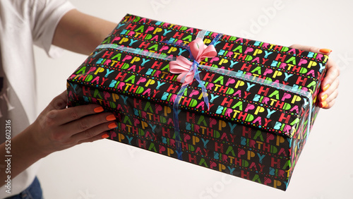 The process of wrapping a gift with women's hands for a birthday in colored gift paper with the inscription "happy birthday"