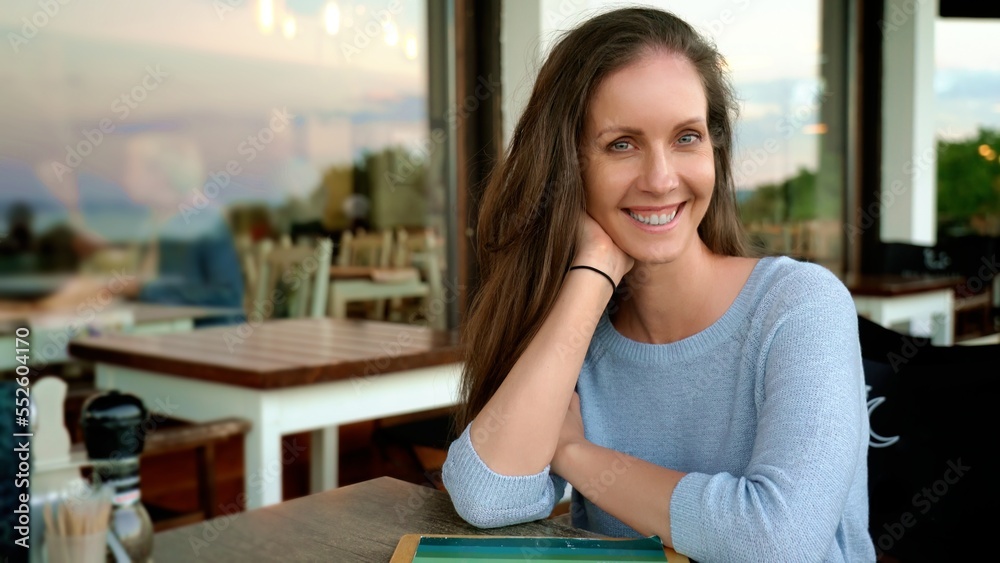 Portrait of happy woman sitting on terrace of restaurant or cafe, smiling. Portrait of happy woman sitting on terrace of restaurant or cafe, smiling.