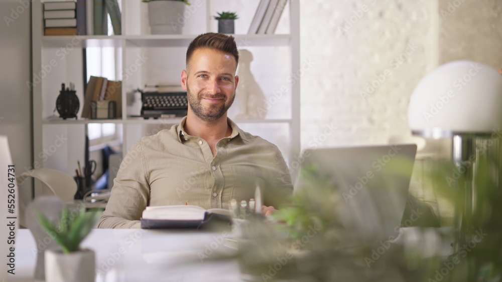 Happy businessman in casual using laptop in home office, Young adult man sitting at desk in study room, working online with computer, browsing the Internet, smiling. Happy businessman in casual using laptop in home office, Young adult man sitting at desk in study room, working online with computer, browsing the Internet, smiling.
