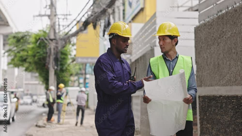Structural engineers and construction workers are holding blueprints inspecting structure. sky train track construction in city. Blue collar wears a safety hardhat while working on construction site.