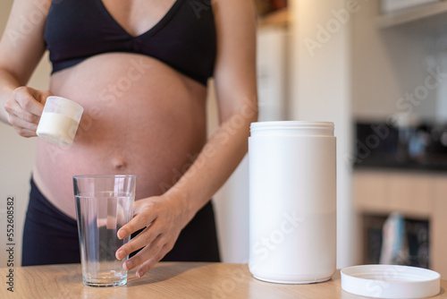 Pregnant woman holding a scoop with whey