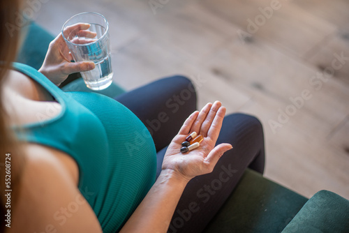 Pregnant woman taking nutritional supplement capsules