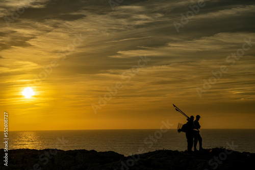 Czarna sylwetka rybaków stojących na klifie, pomarańczowy zachód słońca, przylądek Świętego Wincentego (port. Cabo de São Vicente) Portugalia