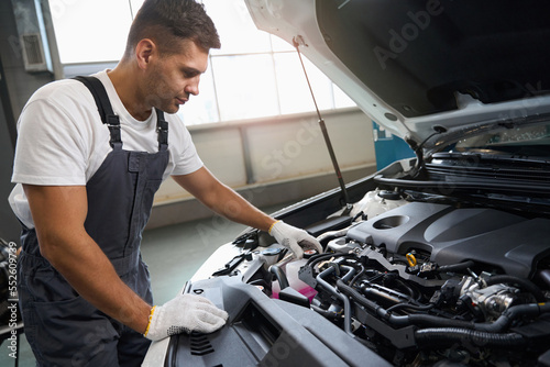 Portrait of handsome man checking parts of automobile