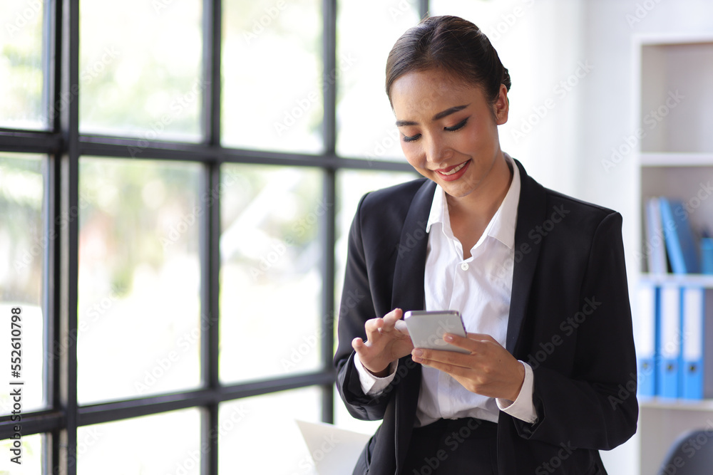 Attractive Asian businesswoman in office checking work schedule on smartphone. Attractive Asian businesswoman in office checking work schedule on smartphone.