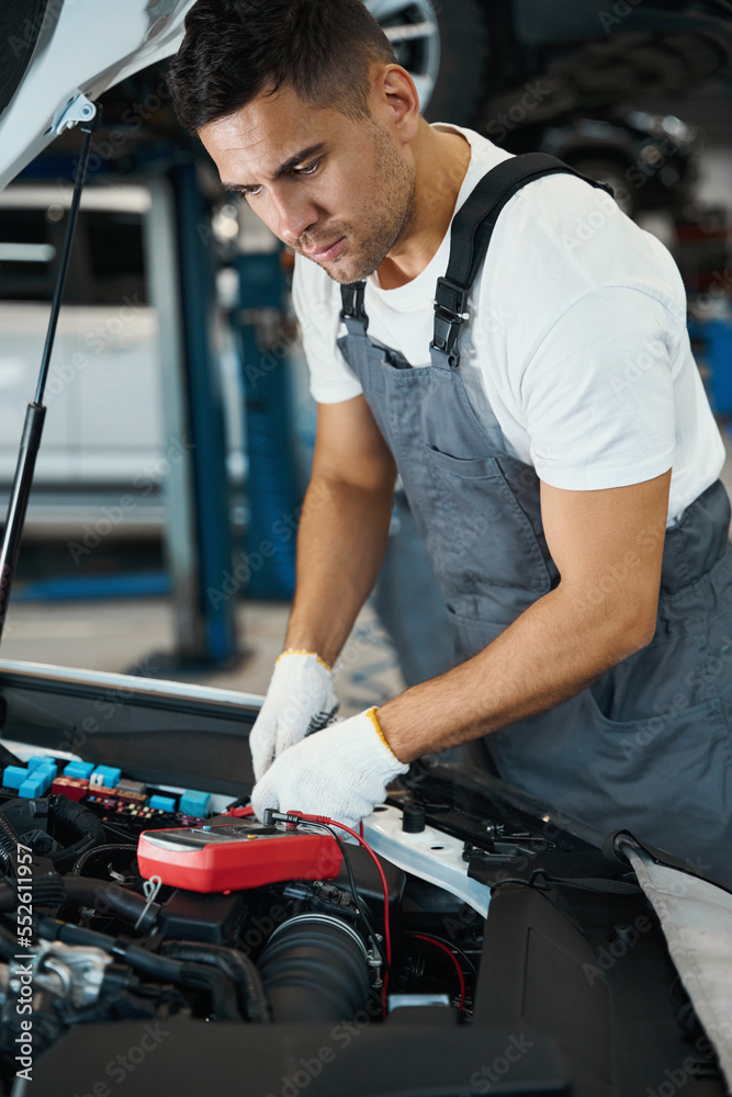 Portrait of mechanic checking technical condition of battery Portrait of mechanic checking technical condition of battery