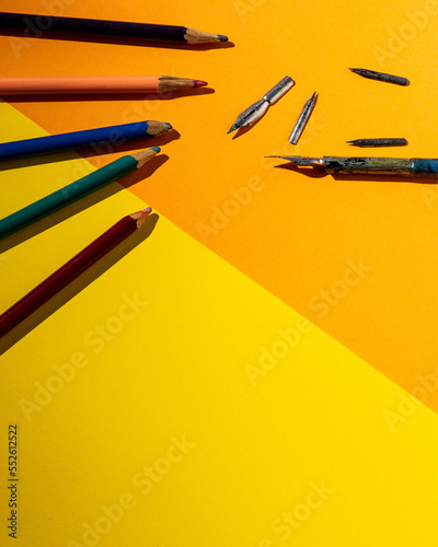 Pencils and feathers on a yellow background