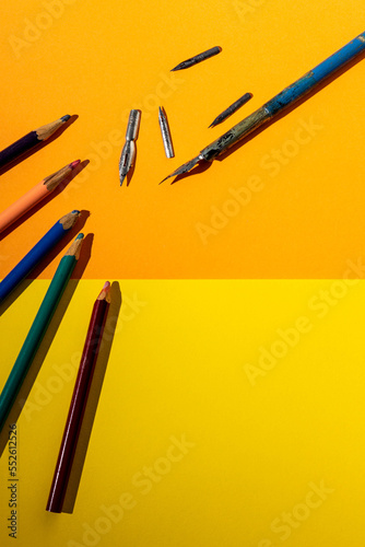 Pencils and feathers on a yellow background.