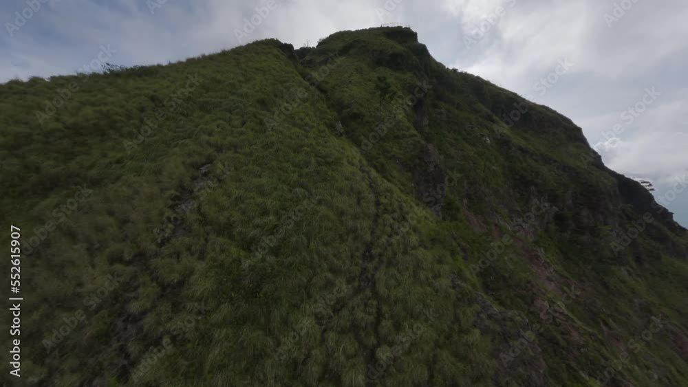 Asian mountain volcano crater ridge summit cloudy sky village landscape aerial view. FPV sports drone raising up shot natural volcanic peak altitude atmosphere tropical scenery cloudscape cinematic 4k Asian mountain volcano crater ridge summit cloudy sky village landscape aerial view. FPV sports drone raising up shot natural volcanic peak altitude atmosphere tropical scenery cloudscape cinematic 4k