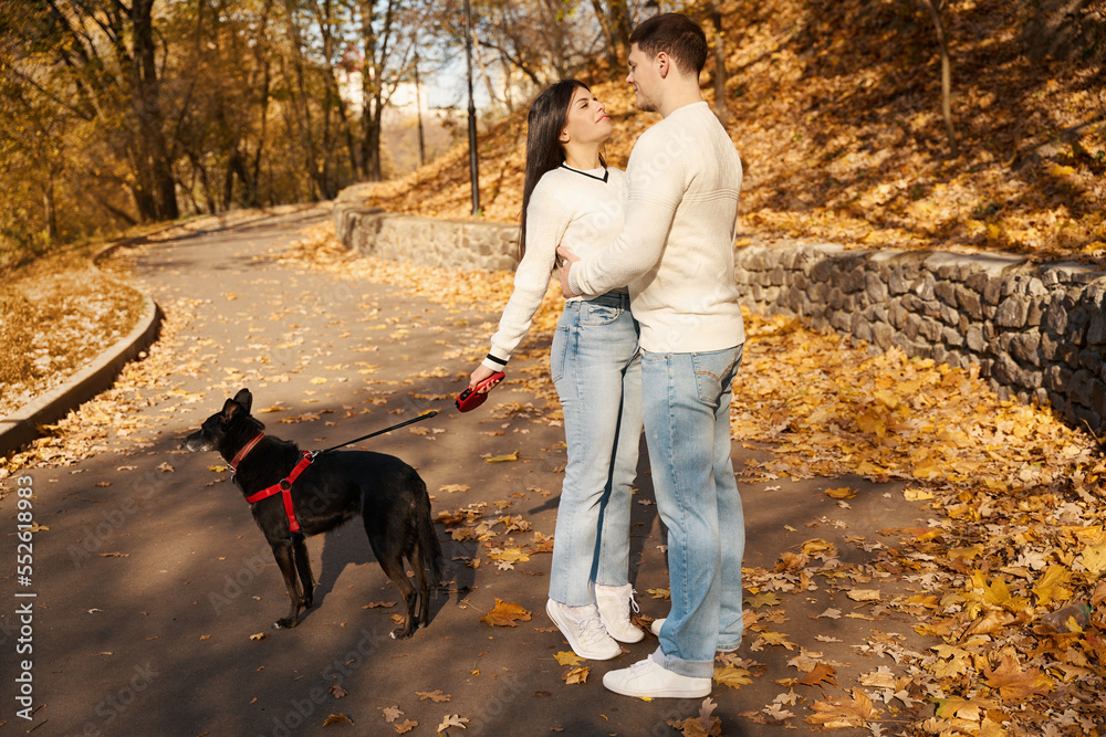 Guy in light sweater hugs his girlfriend in landscape alley Guy in light sweater hugs his girlfriend in landscape alley