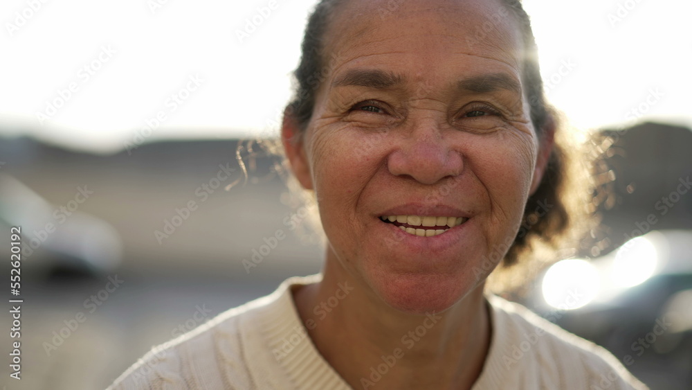Joyful hispanic older woman portrait face smiling and laughing. Happy natural casual South American senior lady standing outdoors
