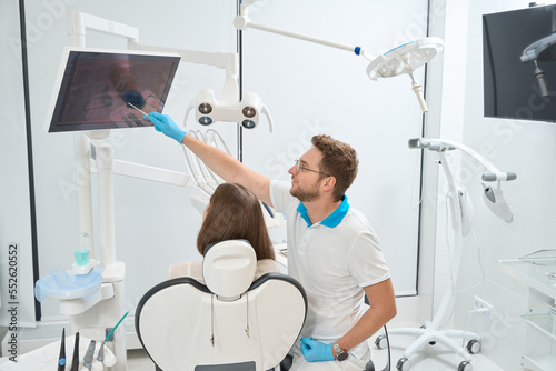 Dentist showing caries on virtual dental radiograph to patient