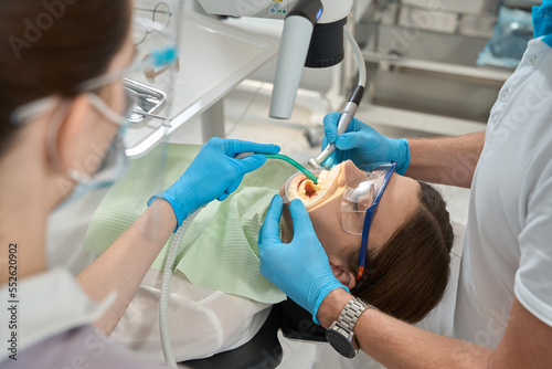 Experienced doctor conducting dental calculus removal under microscope